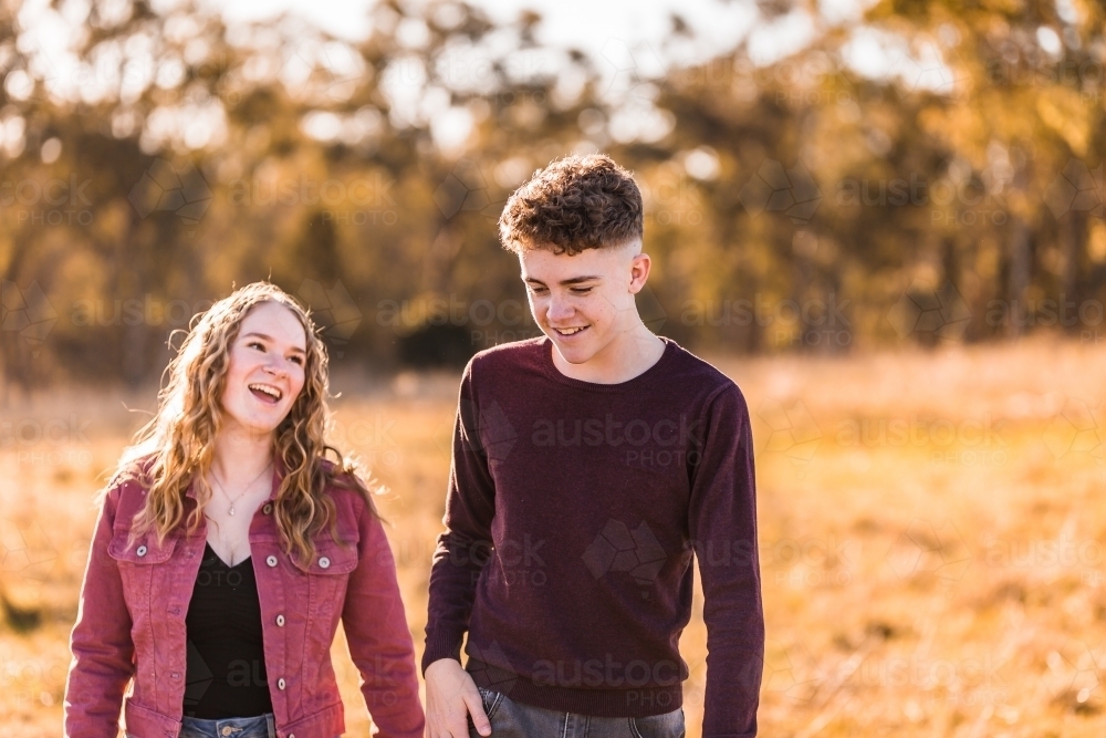 Teen boy and girl walking outside talking and happy - Australian Stock Image