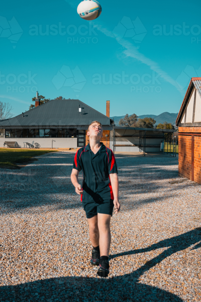 Image of Teen boy playing with rugby ball in the morning before school ...