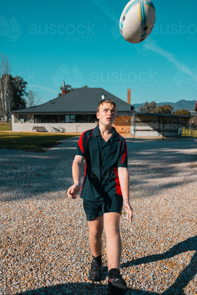 Image of Teen boy playing with rugby ball in the morning before school ...