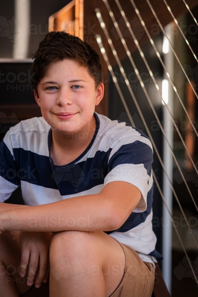 teen boy sitting on stairs at home - Australian Stock Image