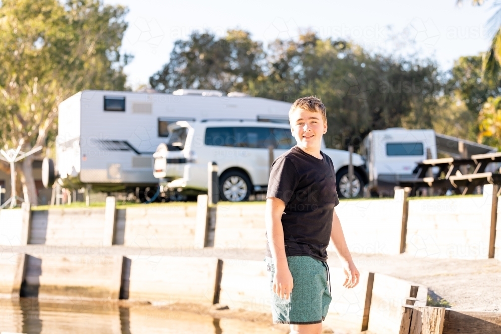 Image of Teen boy smiling at caravan park on family holiday - Austockphoto
