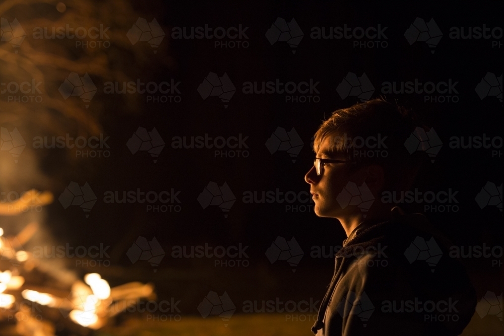 Teen boy standing near bonfire - Australian Stock Image