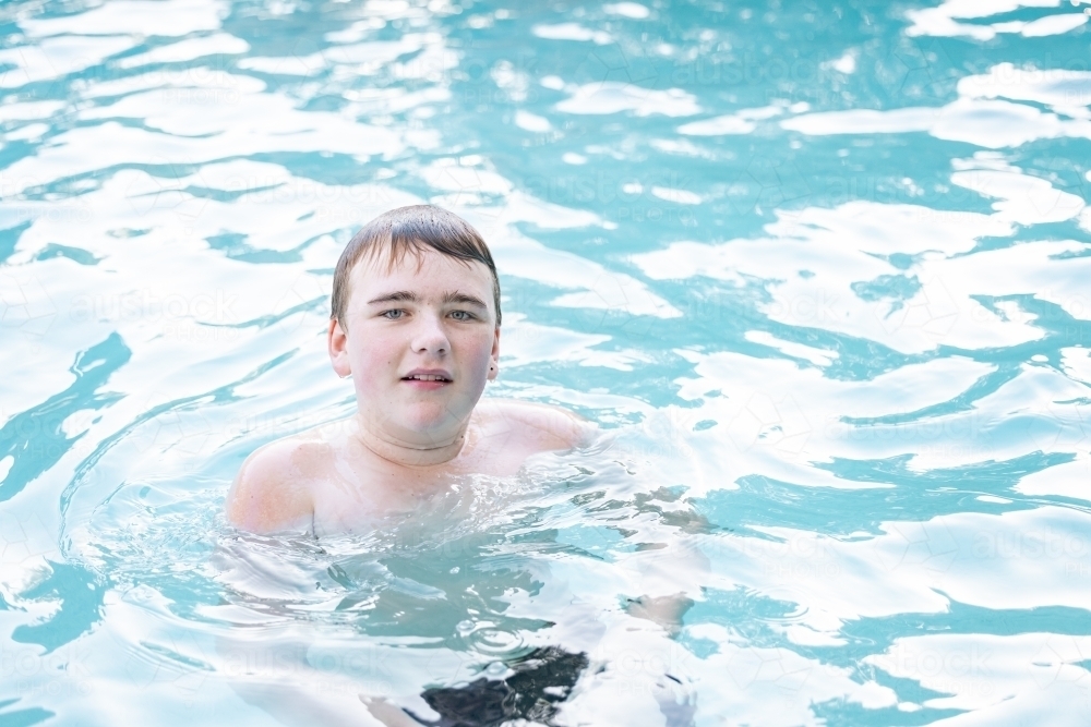 Teen boy swimming in resort pool - Australian Stock Image