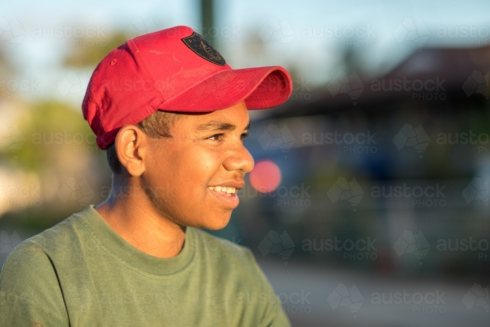 teen boy wearing red cap looking away with blurry background - Australian Stock Image