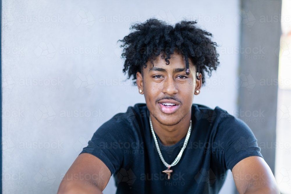 teen boy with curly and frizzy hair wearing black shirt - Australian Stock Image