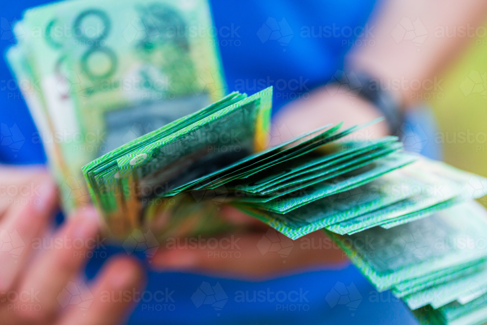 Teen child holding hundreds of dollars of Australian cash educations savings and expenses - Australian Stock Image