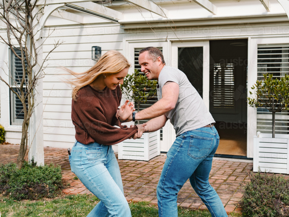 teen daughter and dad playing together outside suburban house entrance - Australian Stock Image