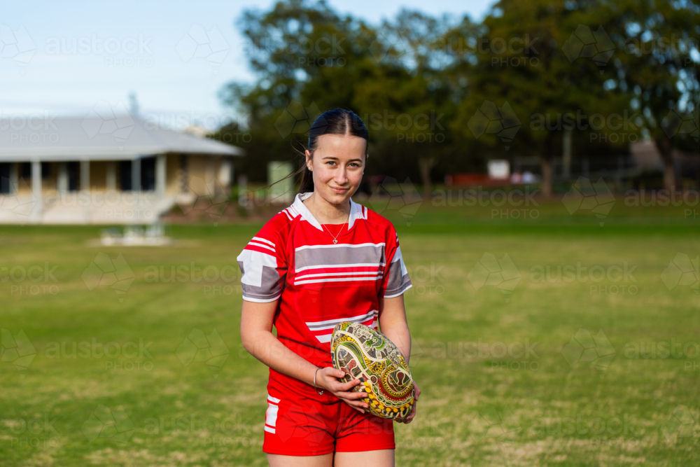 Teen girl AFL player standing on the football ground in sunshine - Australian Stock Image