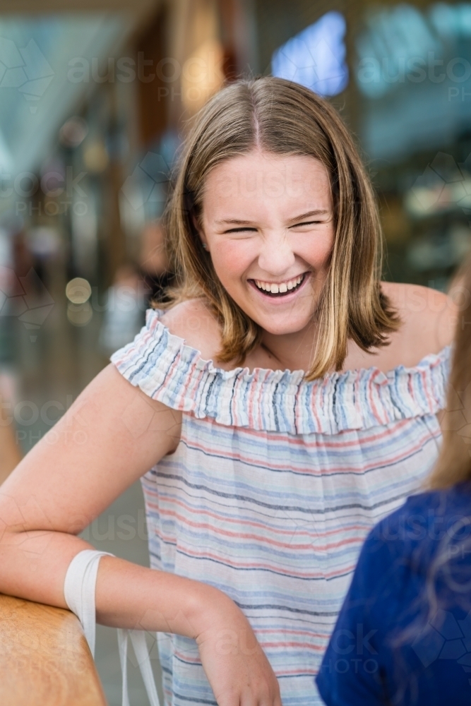 teen girl at shopping mall, laughing - Australian Stock Image