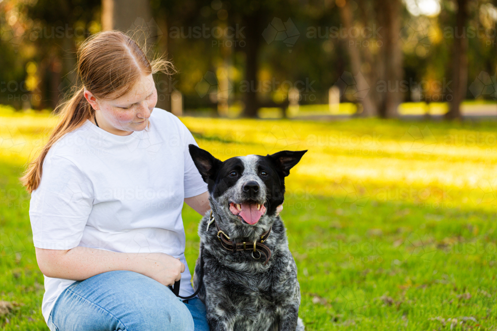 Teen girl beside pet blue heeler Australian cattle dog at park - Australian Stock Image