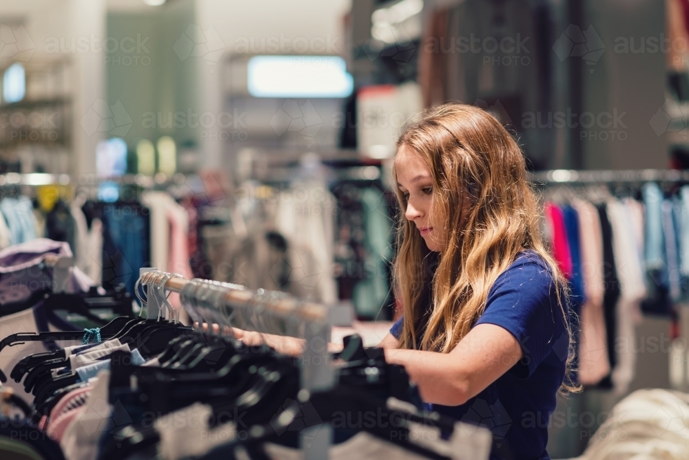 teen girl browsing through clothing rack - Australian Stock Image