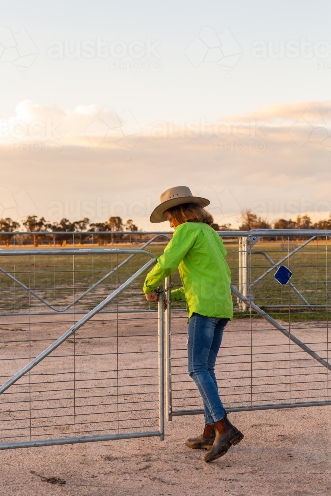 Teen girl closing farm gate - Australian Stock Image
