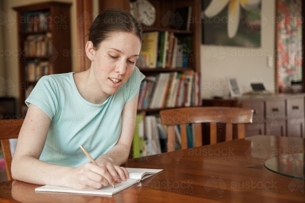 Teen girl doing math work on the table at home - Australian Stock Image