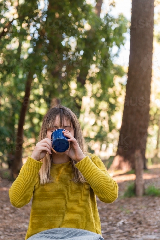 teen girl drinking from a mug on a picnic in the forest - Australian Stock Image