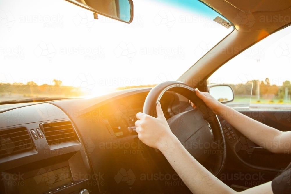 Teen girl driving car with lens flare - Australian Stock Image