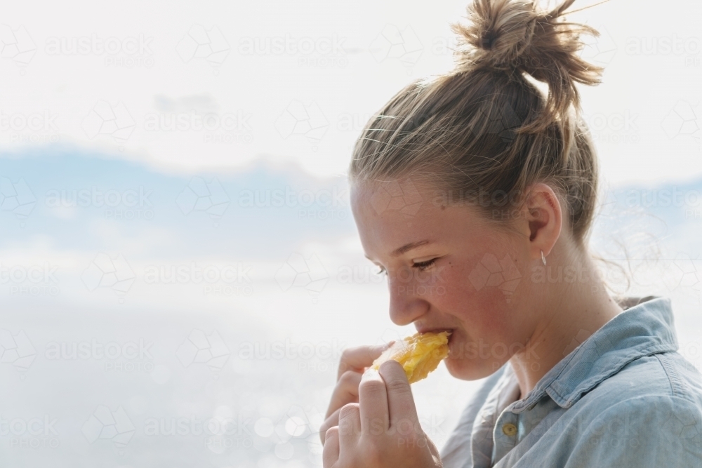 teen girl eating a mango pip - Australian Stock Image