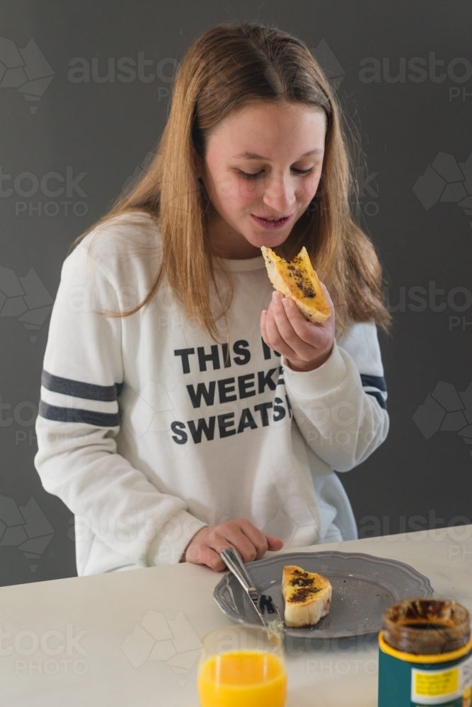 teen girl eating vegemite toast for breakfast - Australian Stock Image