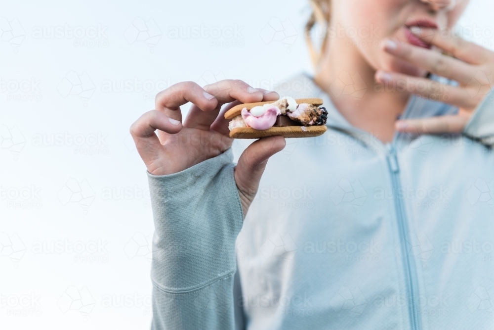 teen girl enjoying smores made with chocolate, marshmallow and biscuit - Australian Stock Image