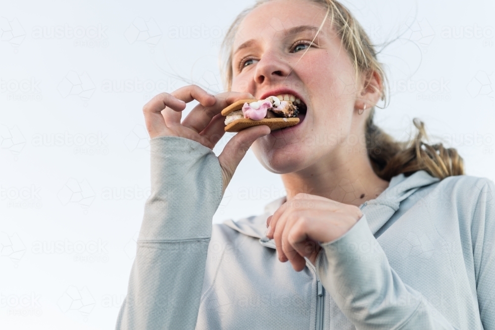 teen girl enjoying smores made with chocolate, marshmallow and biscuit - Australian Stock Image