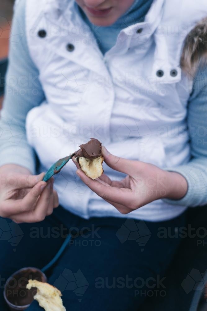 Teen girl filling her campfire bread with chocolate - Australian Stock Image