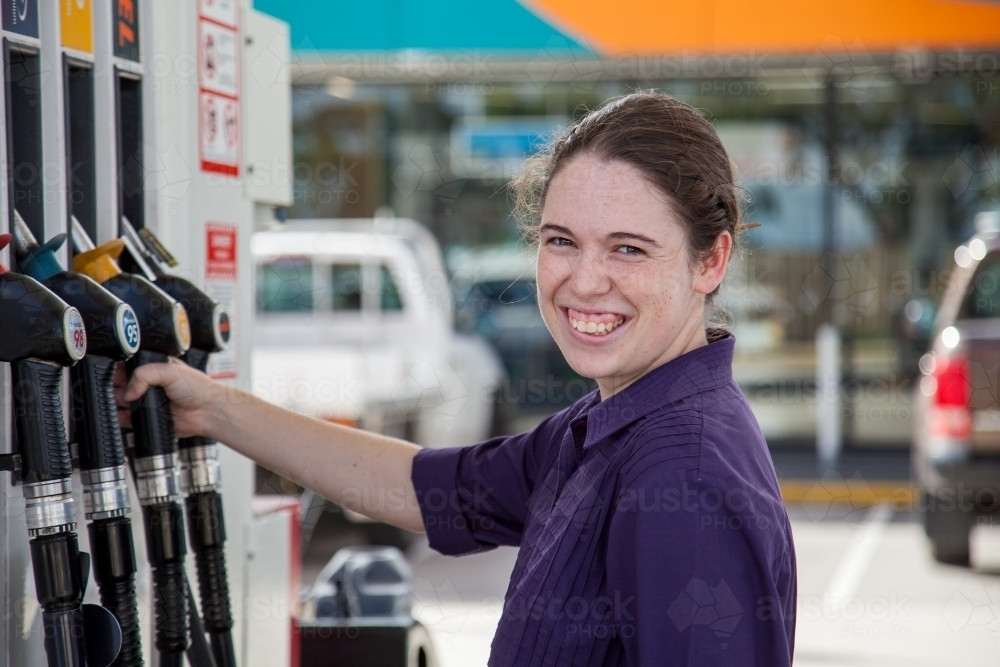 Teen girl filling her car up with petrol at the service station - Australian Stock Image