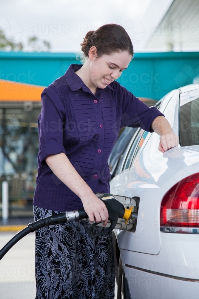 Teen girl filling her car up with petrol at the service station - Australian Stock Image