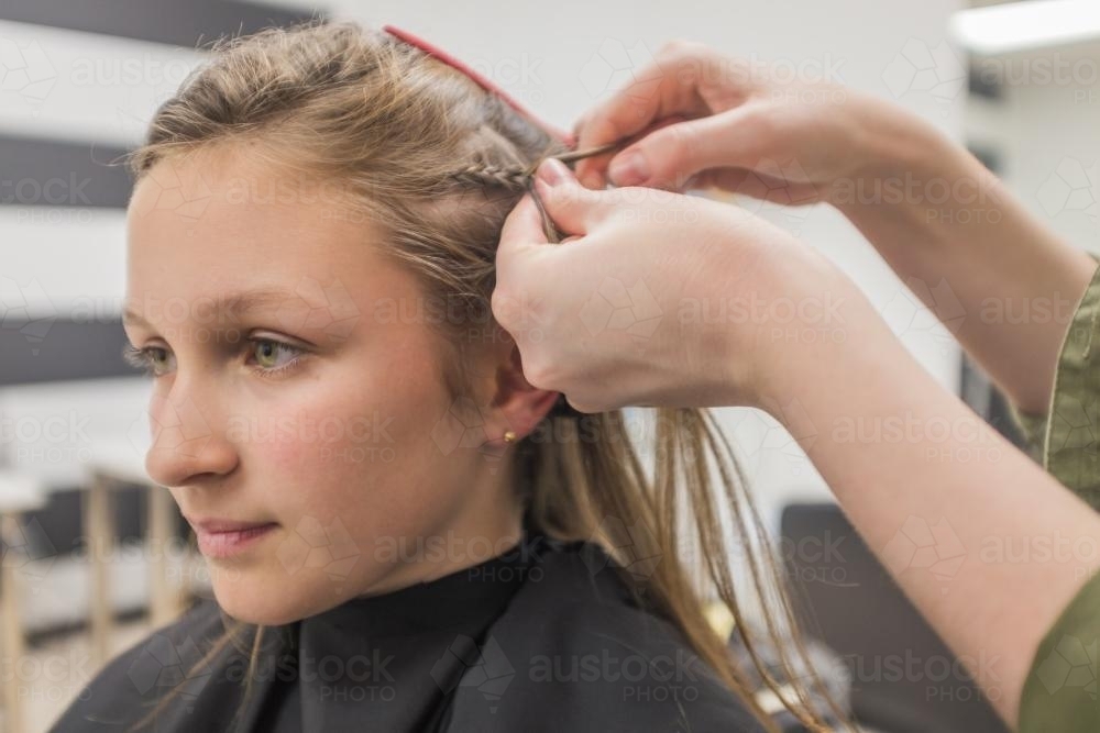 Teen girl having her hair braided at the hairdresser - Australian Stock Image