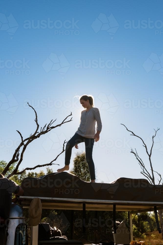 Teen girl helping pack up the roof top tent, from a camping road trip - Australian Stock Image