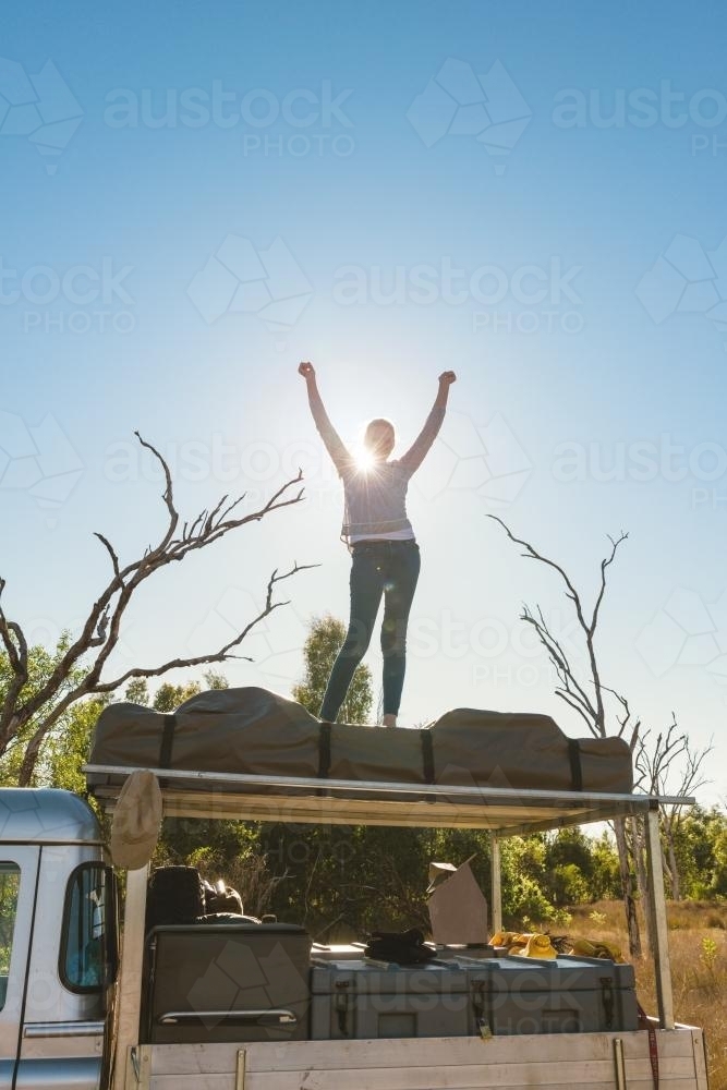 Teen girl helping pack up the roof top tent, from a camping road trip - Australian Stock Image