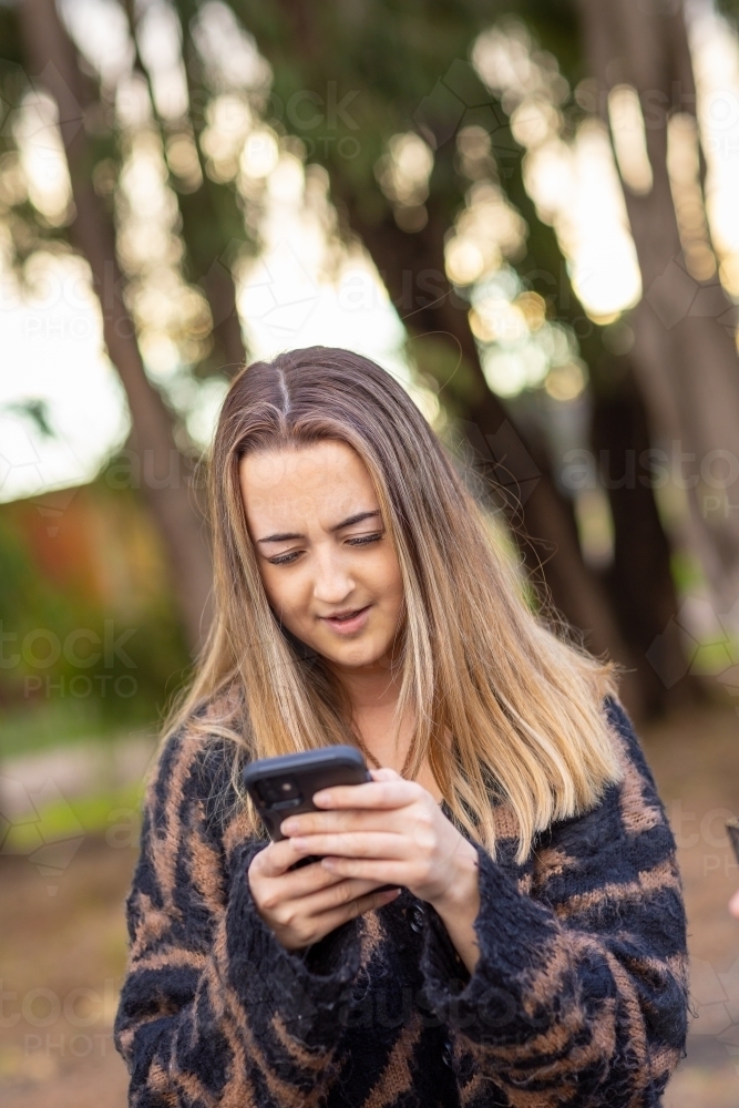 teen girl holding smartphone and looking at it - Australian Stock Image