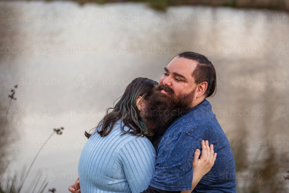 Teen girl hugging her dad against dam water backdrop with copy space - Australian Stock Image