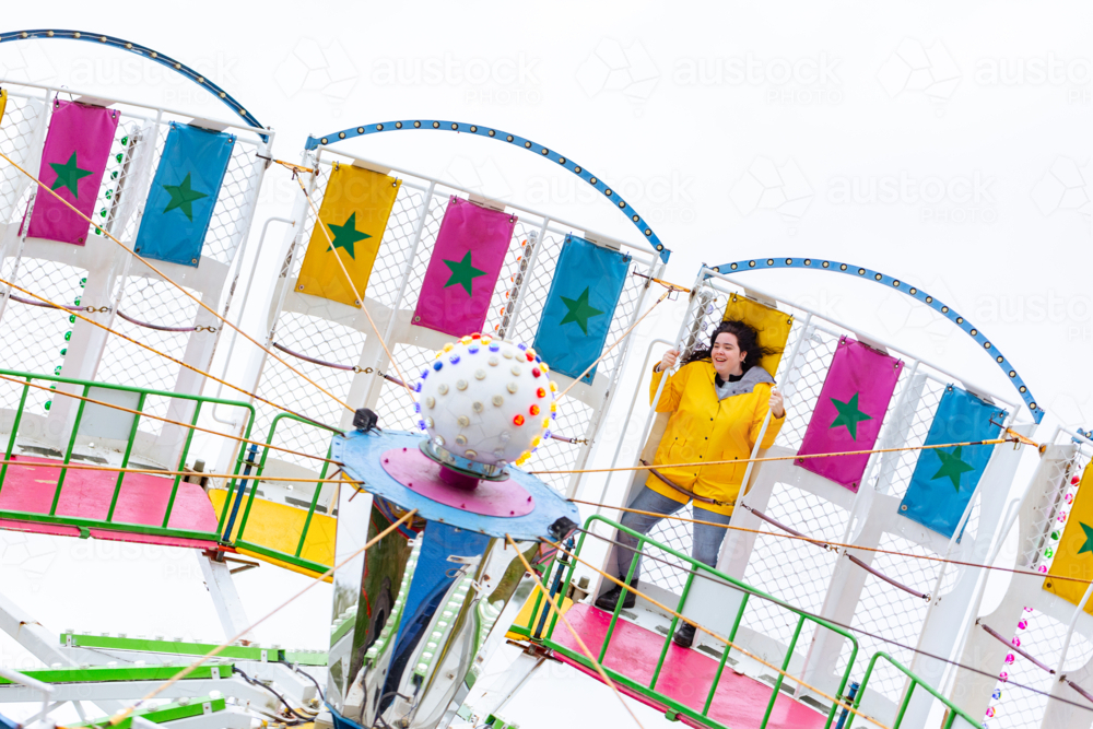 Image of Teen girl in yellow jacket riding on tornado fun fair carnival ...