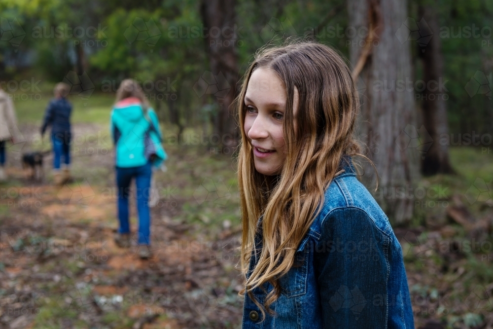 teen girl lagging behind a group of kids in a forest - Australian Stock Image