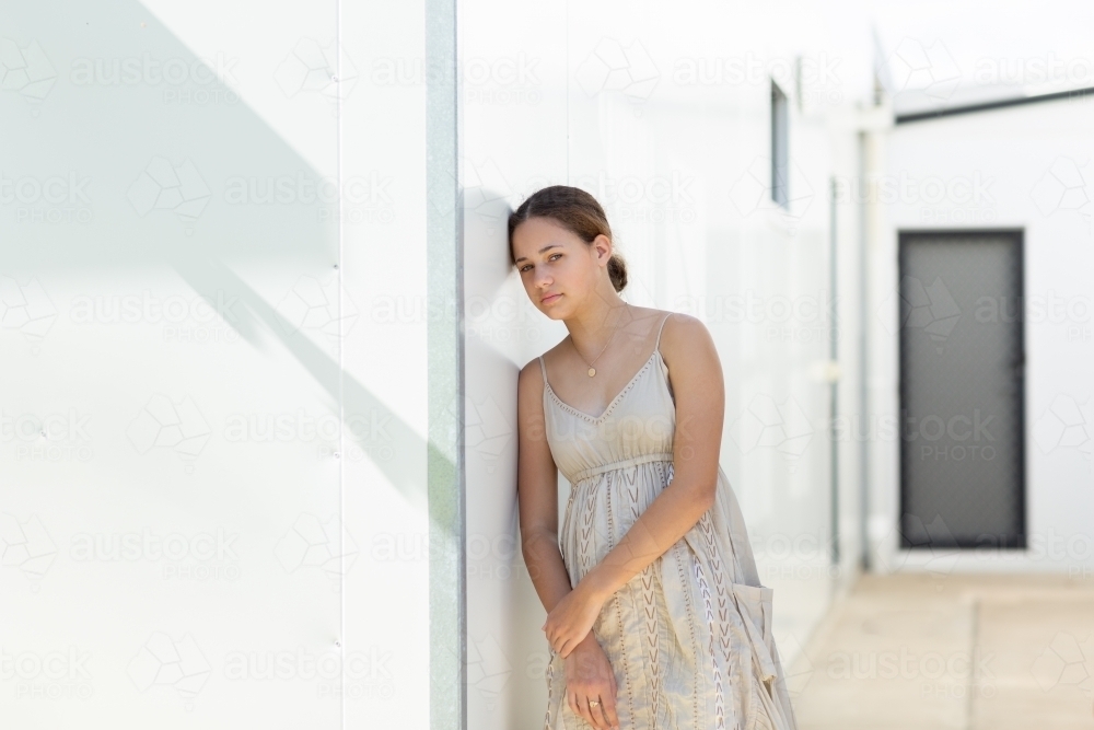 teen girl leaning against a white wall - Australian Stock Image