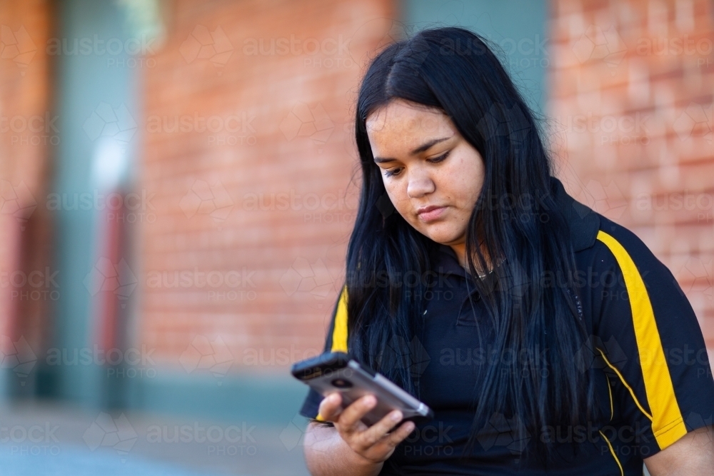 Teen girl looking at smartphone with serious face - Australian Stock Image