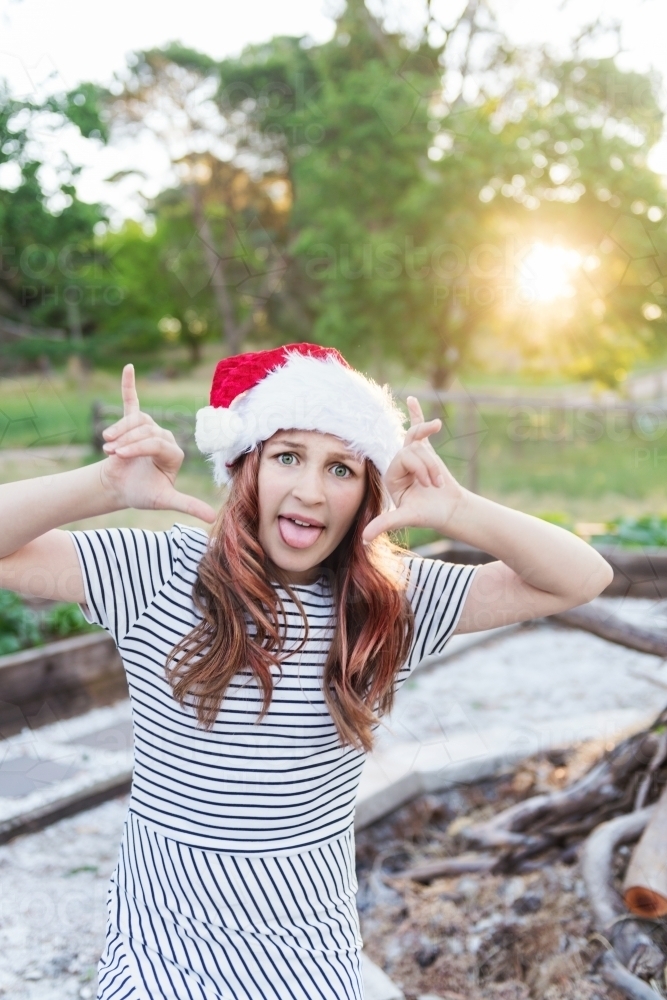 teen girl making silly faces, standing in the afternoon sun at Christmastime - Australian Stock Image