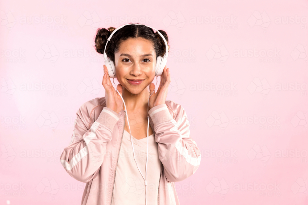 teen girl pin pink listening to music with headphones in studio - Australian Stock Image
