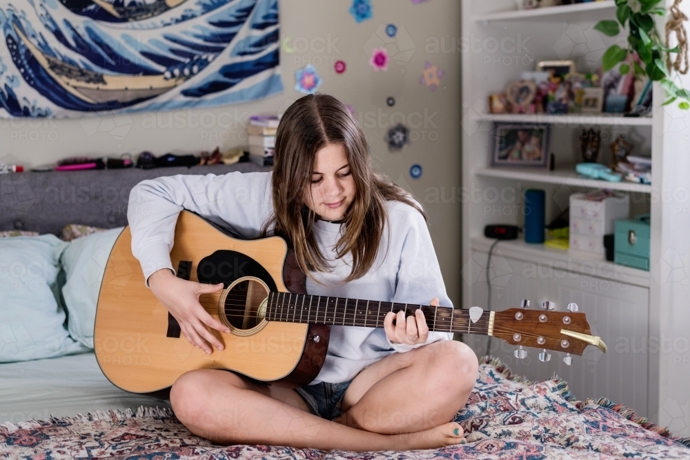 teen girl playing guitar in her bedroom - Australian Stock Image