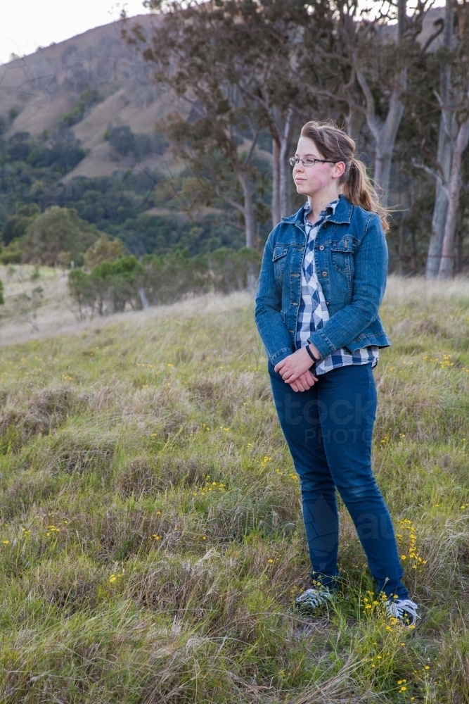 Teen girl standing in a paddock at dawn - Australian Stock Image