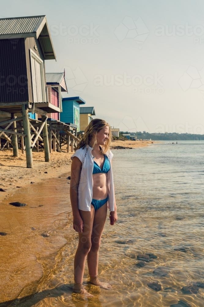 Teen girl standing in the sea at the beach wearing a bikini - Australian Stock Image