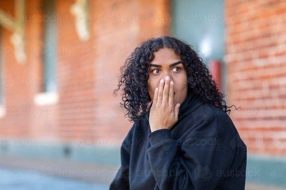 teen girl surprised with hand over mouth and nose - Australian Stock Image