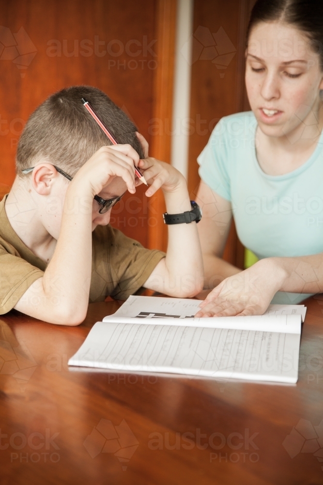 Teen girl teaching young boy at home - Australian Stock Image