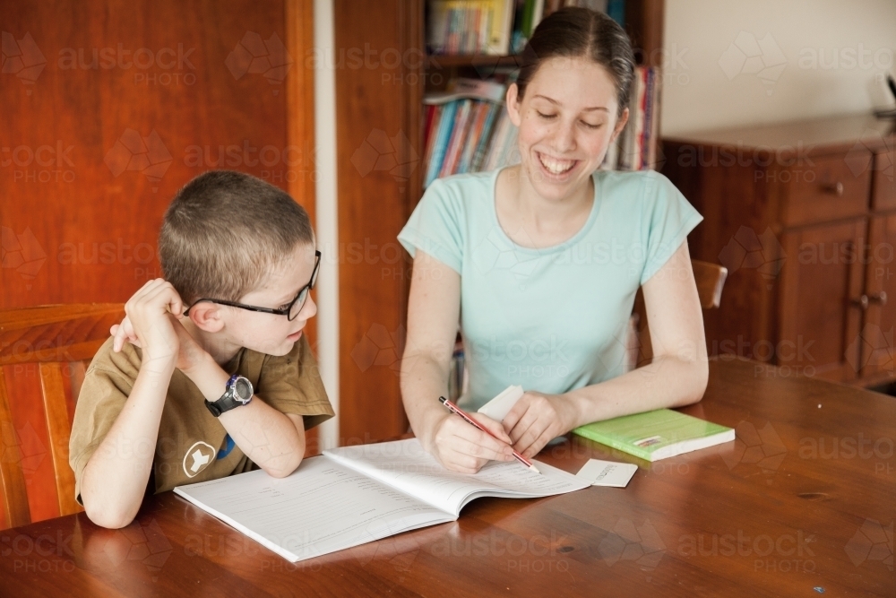 Teen girl teaching young boy at home - Australian Stock Image
