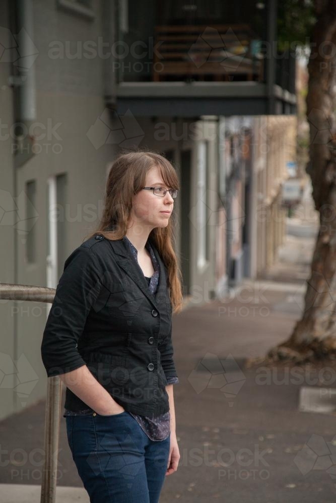 Teen girl waiting on a street on overcast day - Australian Stock Image