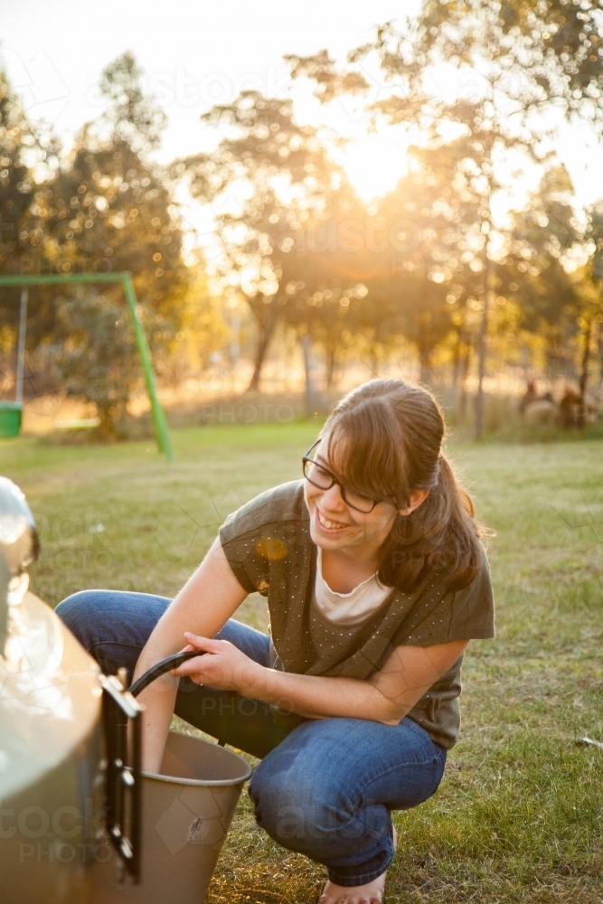 Teen girl washing family car in natural afternoon sunlight - Australian Stock Image