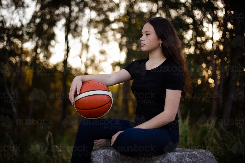 teen girl with basketball on knee - Australian Stock Image