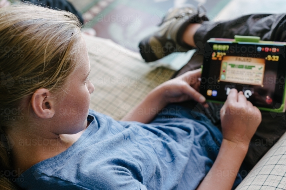 teen girl with iPad on sofa - Australian Stock Image