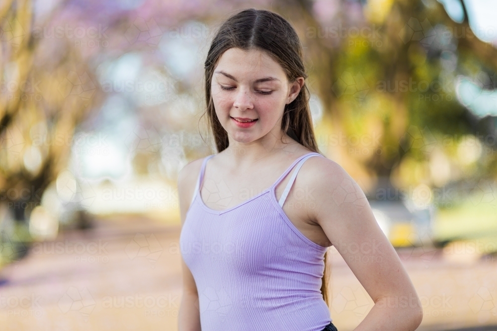 Teen girl with long hair looking down - Australian Stock Image