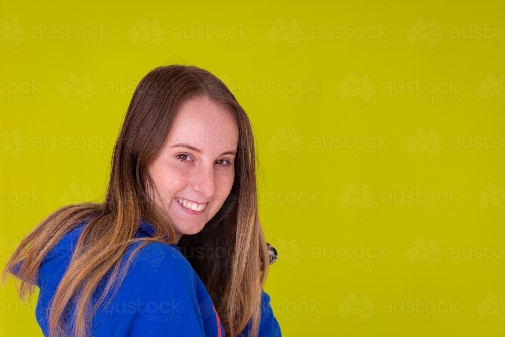 teen girl with long hair wearing blue against a green background - Australian Stock Image