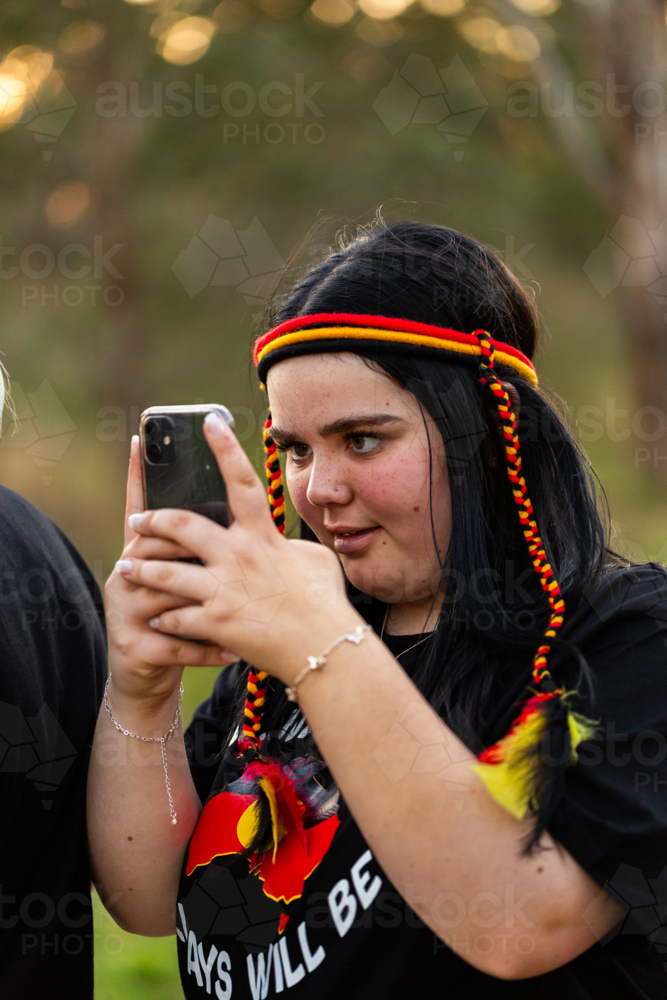 Teen girl with mobile phone out filming with camera - Australian Stock Image